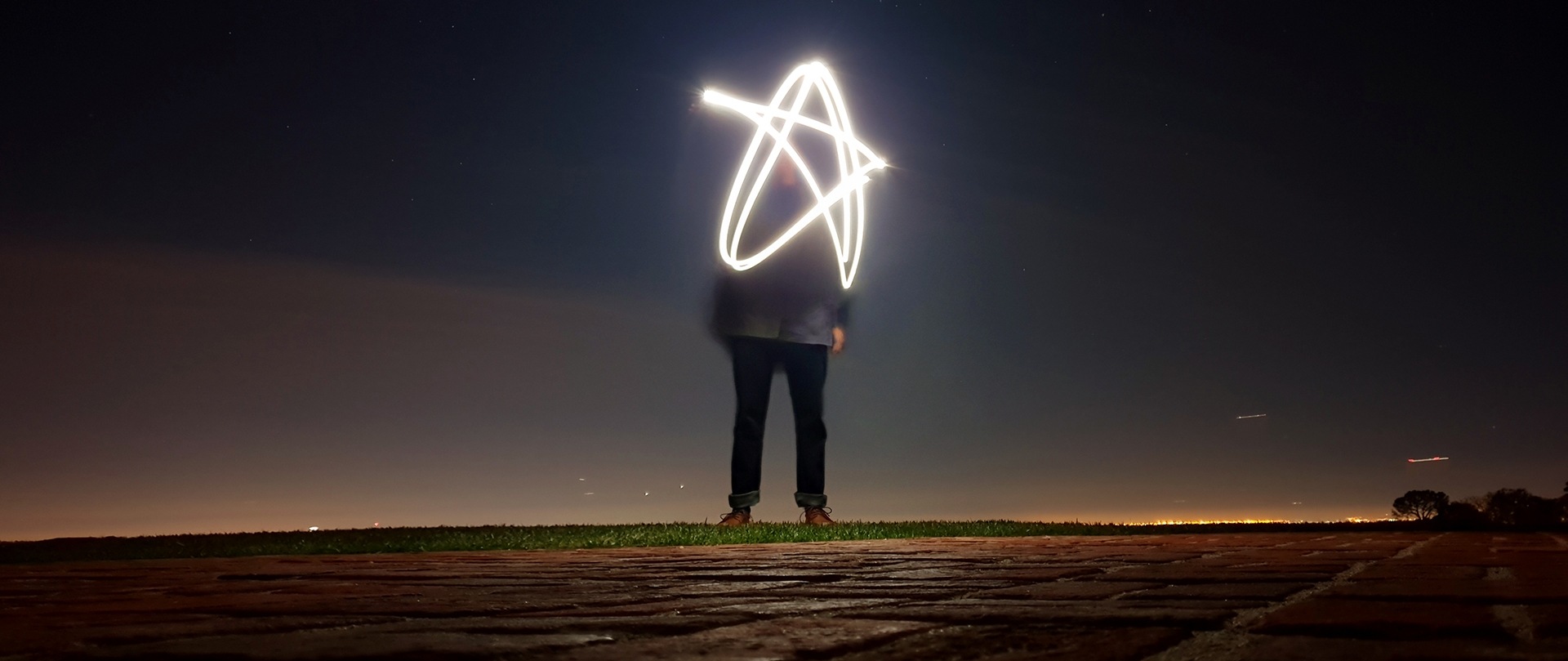 Foto de una persona creando pinturas de luz en forma de estrella.