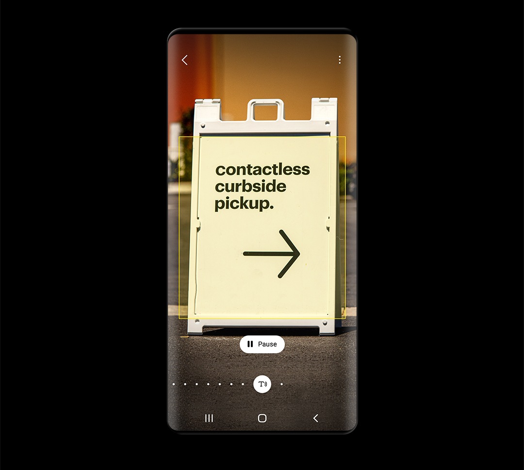 La pantalla del teléfono muestra un letrero en forma de A con el texto "recolección en la acera sin contacto", identificado por Bixby Vision, y un botón de pausa debajo de la imagen.