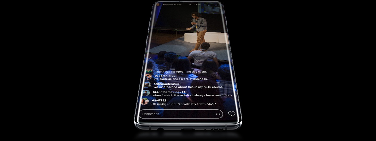 Un Galaxy S10 Plus recostado sobre su parte trasera, visto desde abajo desde un ángulo ligero, con una presentación transmitida en vivo superpuesta en la pantalla con comentarios.