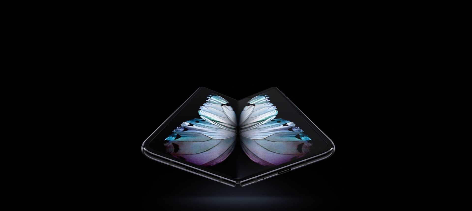 Un teléfono Galaxy Fold de color negro cosmos visto en un ángulo ligero desde abajo, con una gráfica de una mariposa multicolor en pantalla.