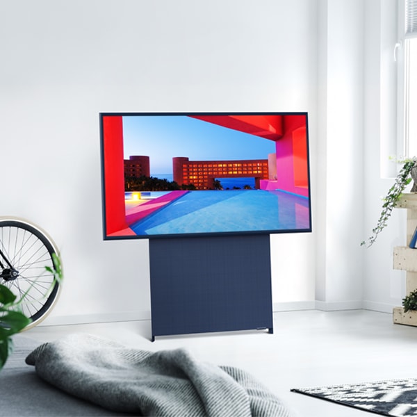 The Sero stands in a white room, with the screen in horizontal mode, displaying a building on the screen.