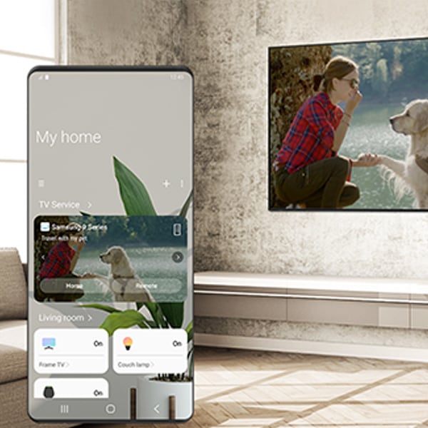 SmartThings app opened on the phone screen, QLED TV in the backdrop of the image
