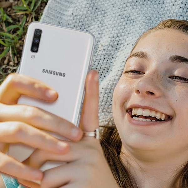 A girl holding and smiling to her Samsung Phone