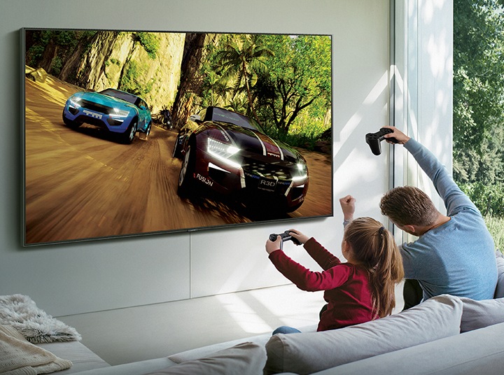 A man and his daughter are playing a Steam game on Samsung Smart TV. The game is being streamed through Samsung Steam Link.