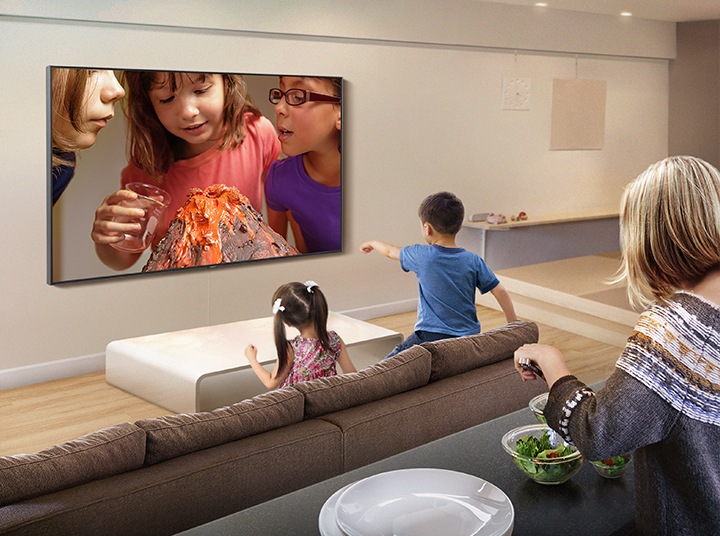 Children are watching kids' science experiment video in the living room, and behind them, their mother is serving a salad at the island table. The experiment video is being streamed through YouTube app on Samsung Smart TV.