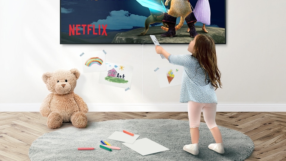 A little kid using smart remote to control QLED TV