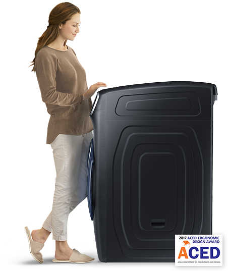 A woman stands by the washing machine. She appears to be loading laundry.