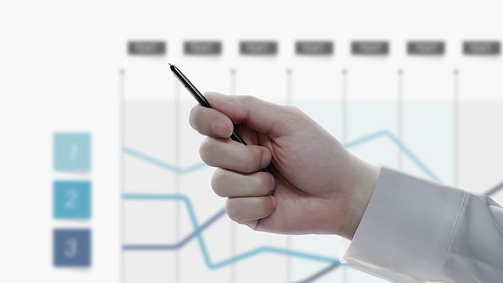 Image simulée d’une personne avec le S Pen en main, avec une présentation d’un graphique linéaire en arrière-plan. Lorsque la personne clique sur le bouton du S Pen, la diapositive de la présentation passe à un autre graphique.