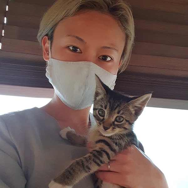 Une femme portant un masque et tenant un chaton dans ses bras