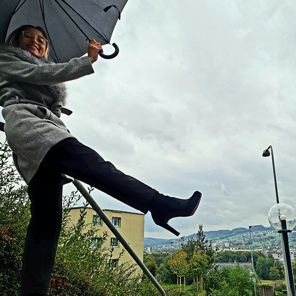 Femme en contreplongée levant la jambe tout en tenant un parapluie