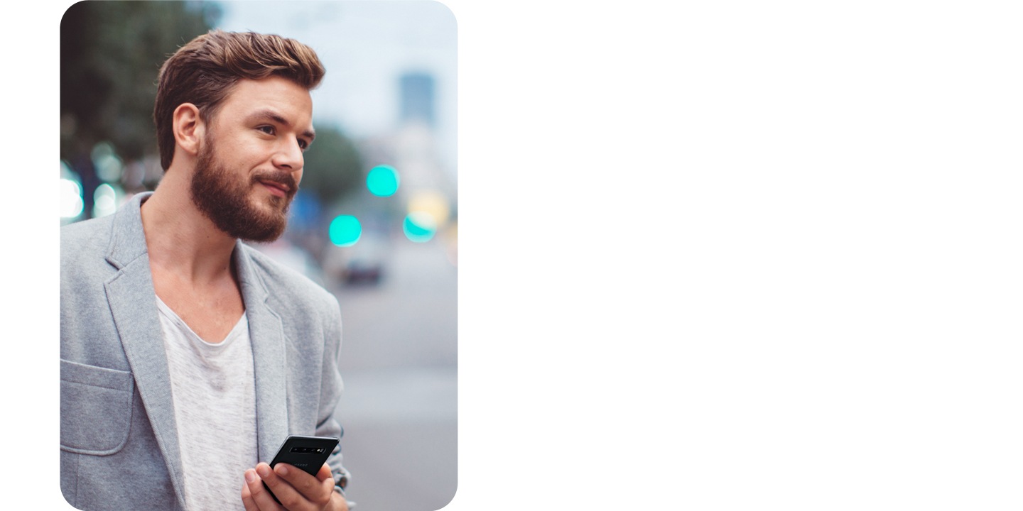 On voit un homme tenant un téléphone traverser une rue bondée.