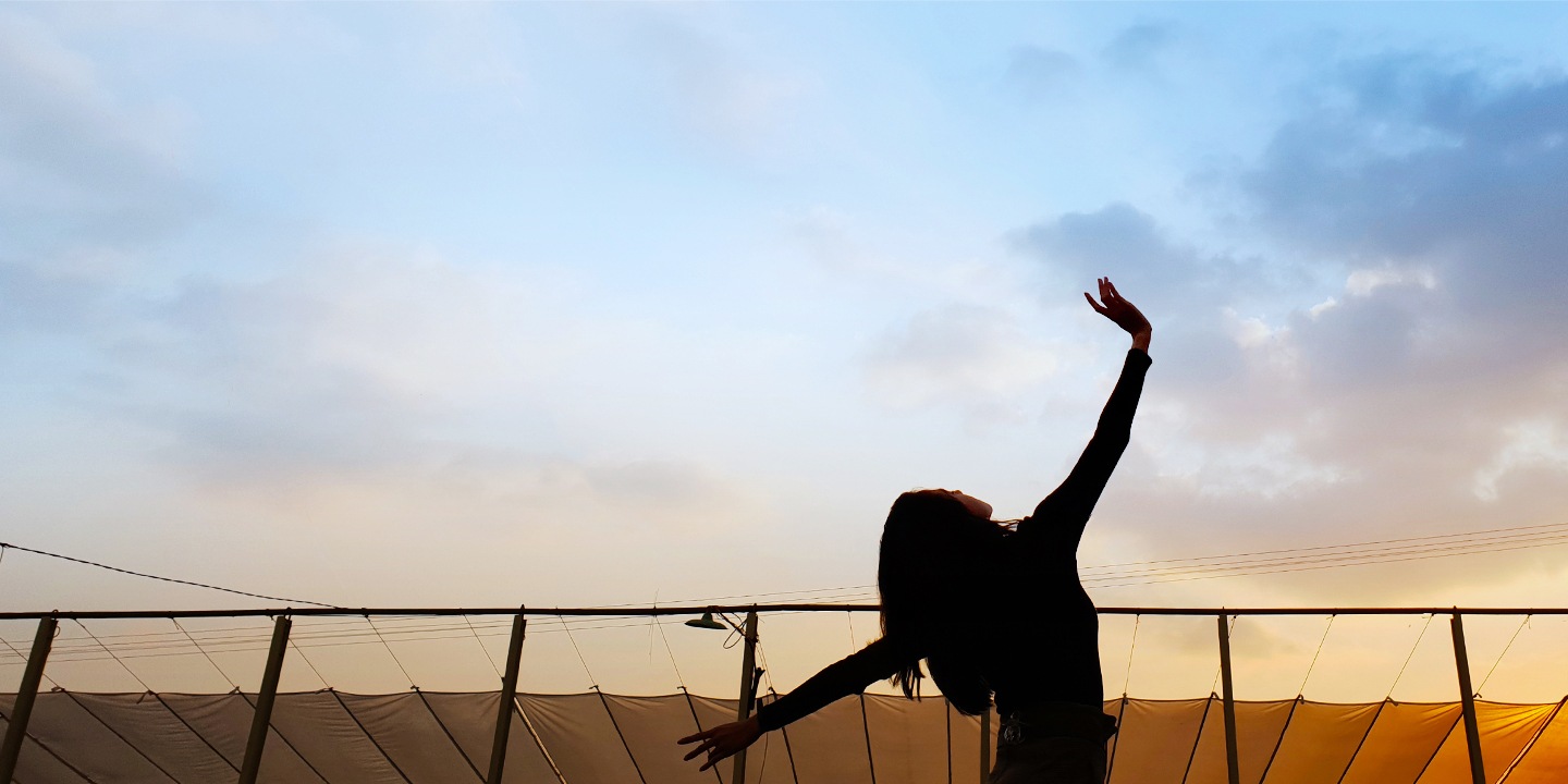 Une femme danse sous le coucher du soleil.