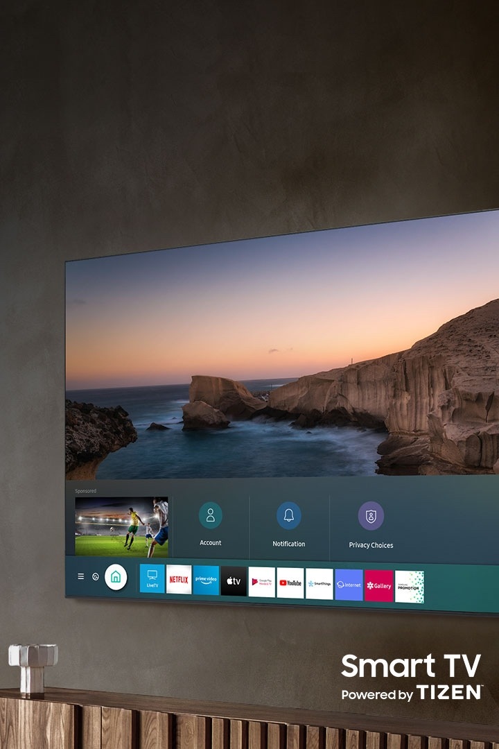 Un téléviseur QLED 2020 Samsung est accroché au mur et affiche le Smart Hub grâce à la Smart TV fonctionnant avec TIZEN.