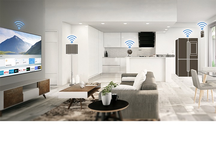 Une pièce principalement blanche, familiale et moderne, avec cuisine et salle à manger à aire ouverte, contenant divers appareils électroménagers intelligents tels qu'un téléviseur, une lampe et un réfrigérateur intelligents dans la maison qui montrent une connectivité facile.