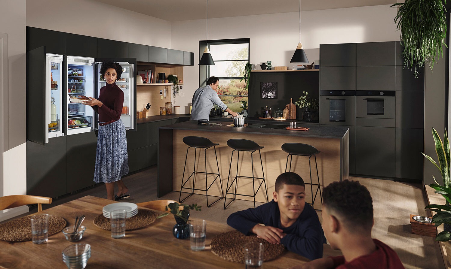 Een gezin in de keuken. De vrouw staat voor een Samsung koelkast.