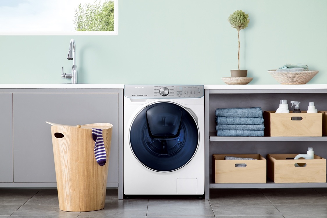 De QuickDrive™ wasmachine in een keuken, met een wasmand ervoor