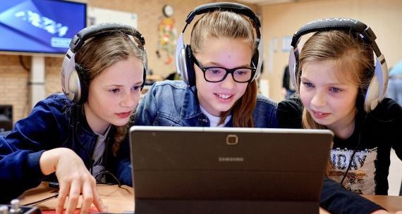 Two girls with headphones on working on a Samsung Laptop