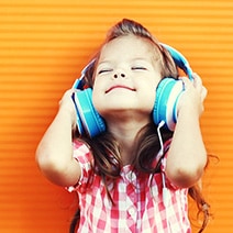 Little girl listening to music with big blue headphones on