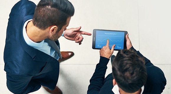 A banker responding to a client while looking up client's financial information on a Samsung tablet