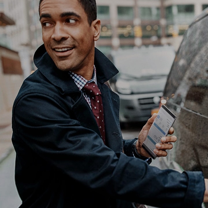 A man holding his Samsung smartphone while he is getting in the car