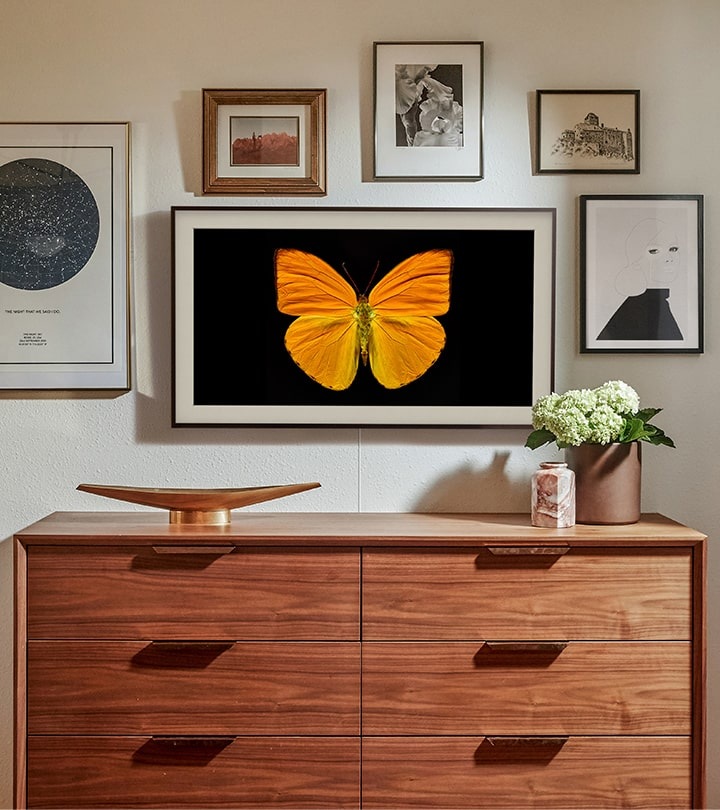A mounted Samsung The Frame TV is turned off and displaying art in Art Mode so it looks just like a real picture frame, creating a personal mini gallery.