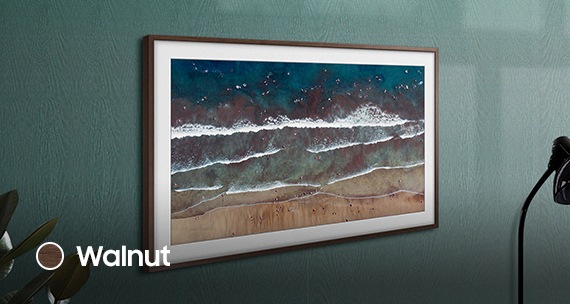 Samsung The Frame TV with walnut bezel is on the wall. Personalise the look of The Frame to complement your style.
