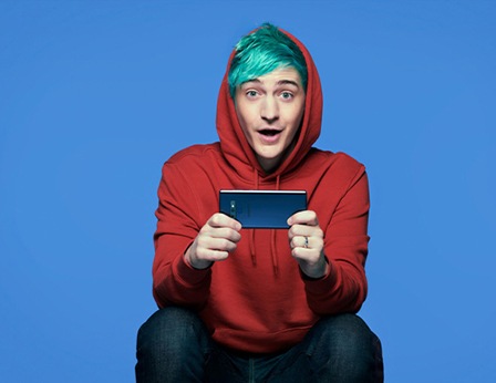 Primer plano del jugador Ninja sobre un fondo azul sosteniendo un Samsung Galaxy S10 prisma negro