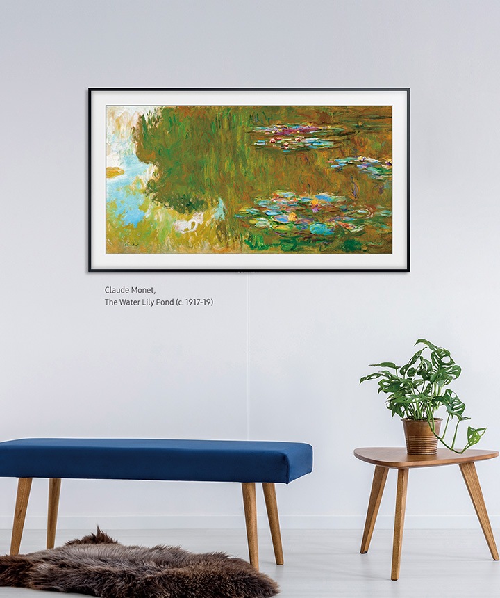 The Frame hanging on a wall above a bench and a table with the basic charcoal black frame.