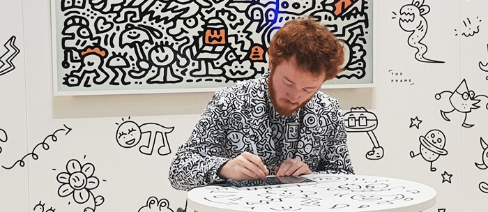 A photo of the Mr. Doodle Drawing Show event venue, with a stage and backdrop covered in hand-drawn doodles.