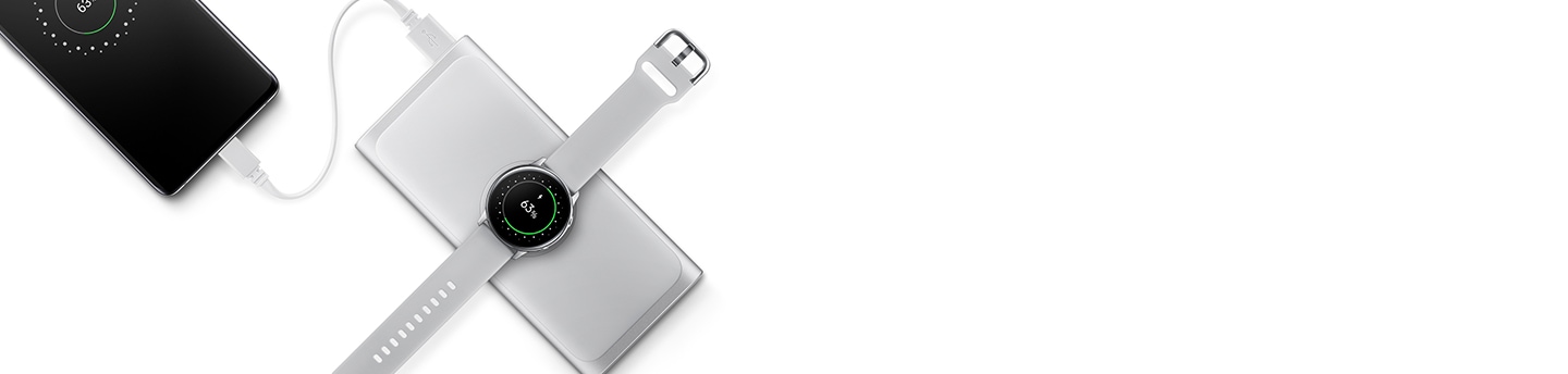 Wireless Battery Pack in Silver with a Galaxy smartphone plugged in and charging, and Galaxy Watch Active2 charging wirelessly