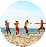 Girls are jumping at a beach.