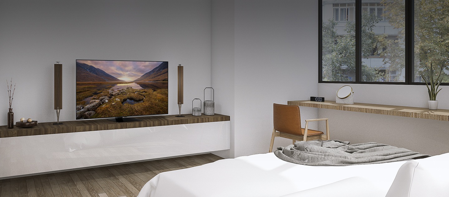 O interior do mesmo quarto, só que desta vez a TV está ligada e as persianas levantadas.