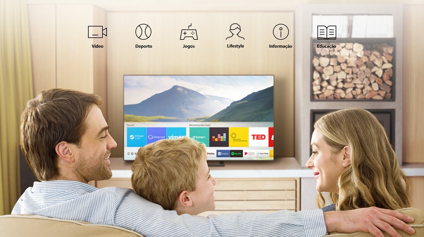 Three people in the living room looking at Smart TV. The Smart Hub interface is displayed against a nature background image on the TV screen. The interface shows various content such as "Steam Live, Internet, Vimeo in" Recent ", Tunein Radio, Deezer, Berliner Philharmonic, TED in" Recommended Apps "and several apps like YouTube, Facebook Video, Google Play Movies & TV and SmartThings.