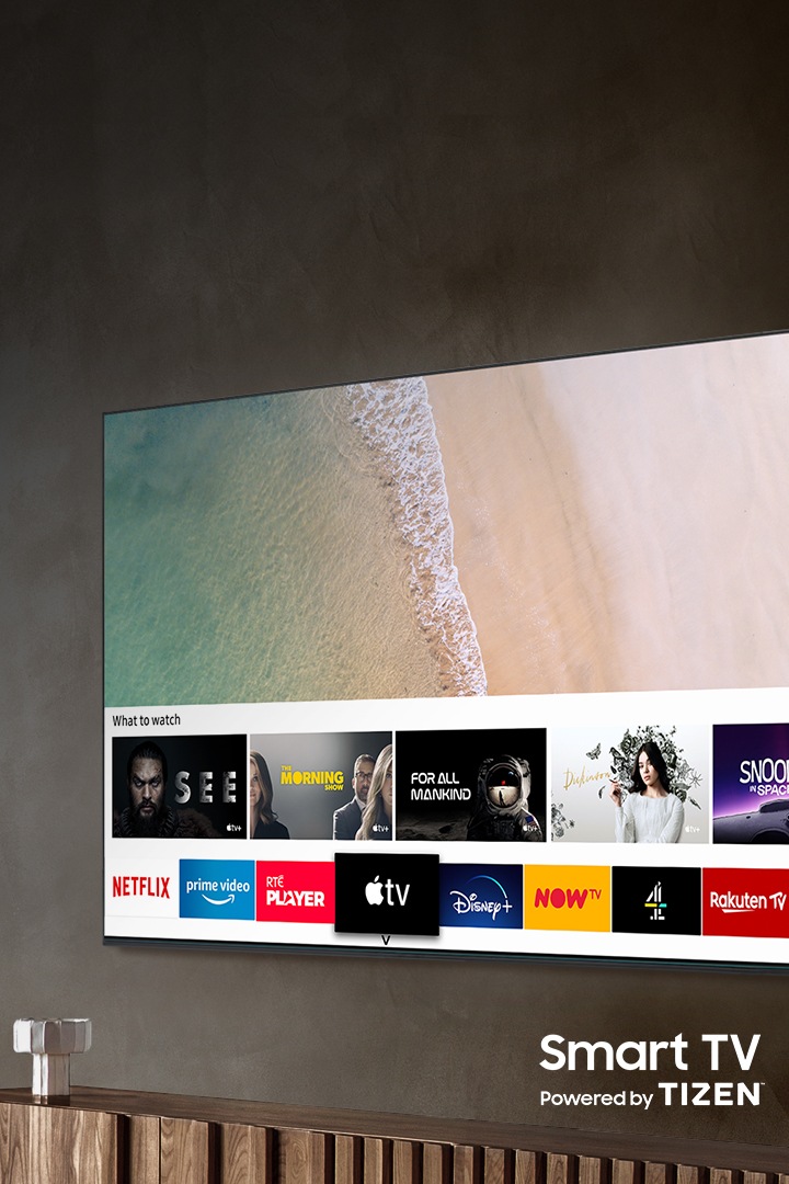 A TV Samsung QLED 2020, pendurada na parede, tem um Smart Hub com Smart TV de tecnologia TIZEN.