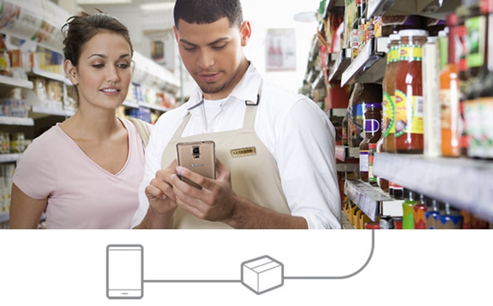 Un vânzător uitându-se pe un smartphone pentru a-şi ajuta clientul