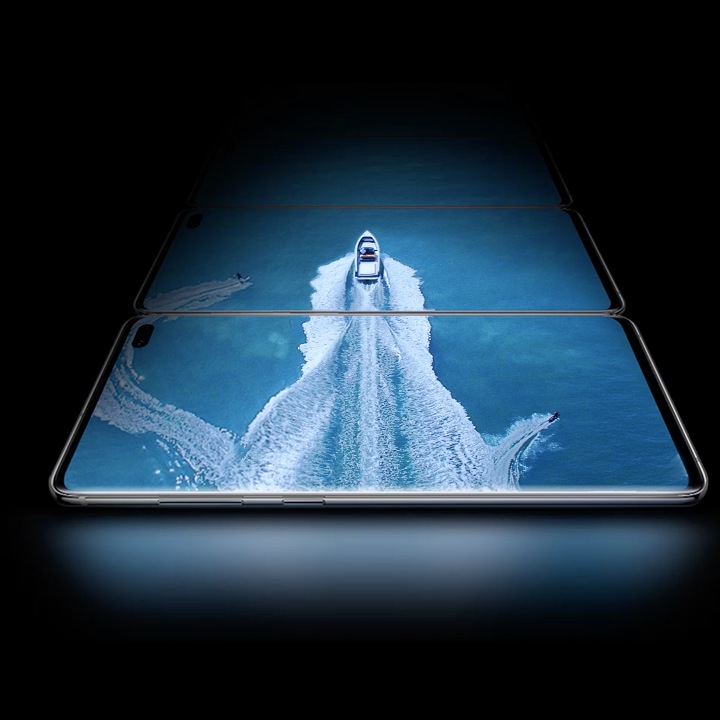 Tри телефони Galaxy S10+ во хоризонтална позиција, над едниот кој е поставен напред, гледано под благ агол од страната на која се наоѓа копчето Bixby и копчето за јачина на звукот. На три екрани се гледа фотографија на чамец во вода со двајца скијачи на вода сликана од горе, и покажува можност за ширење на Infinity-O екранот.