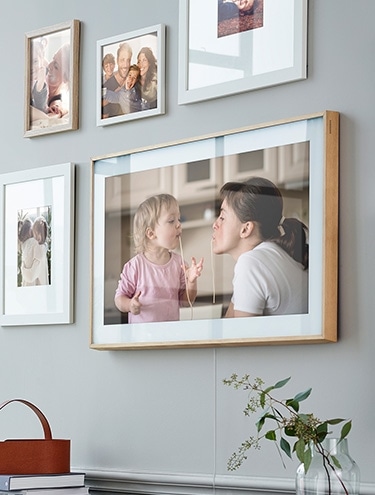The Frame on the wall displaying a family photo among other picture frames.