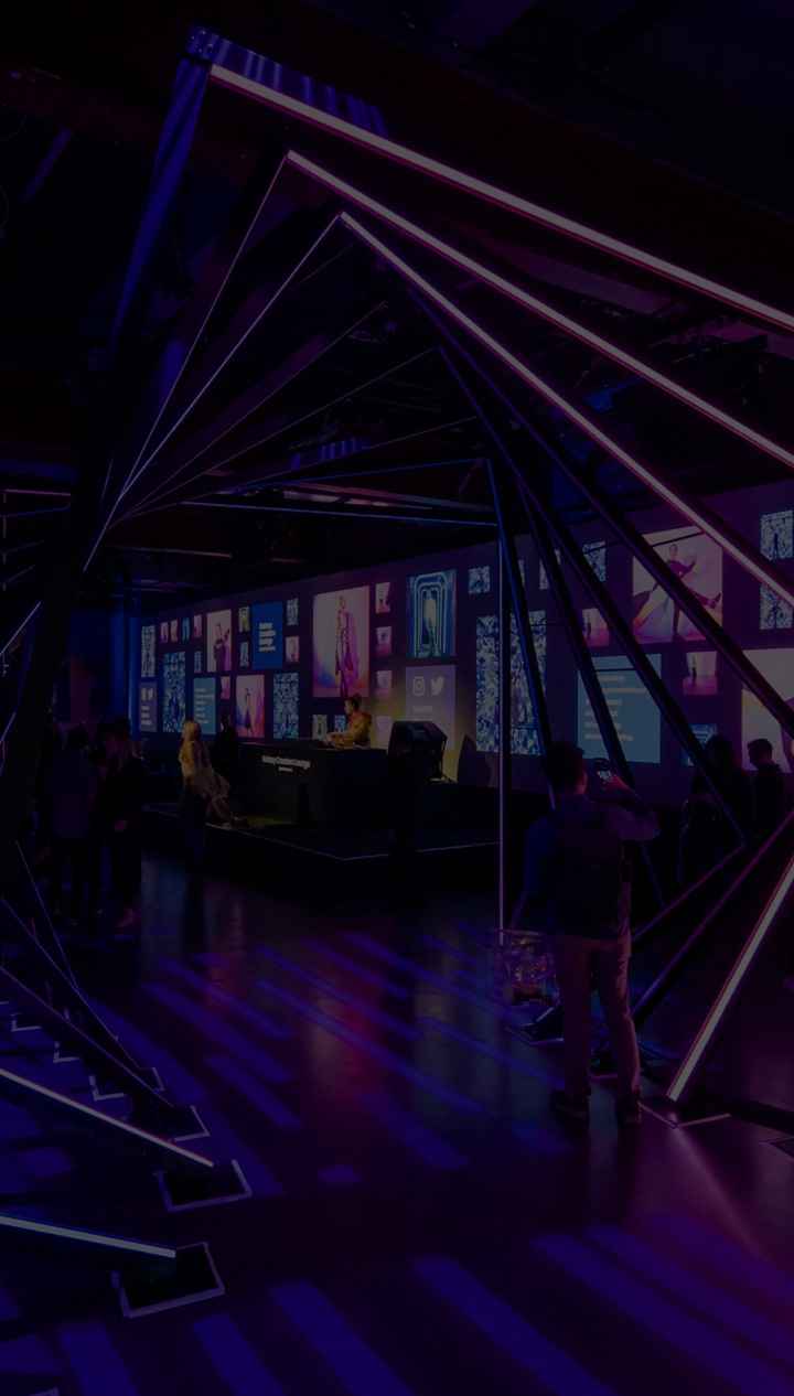 Influencers gathered in the Creators Lounge event space. You can see a colorful light installation in the front and a DJ stage and bar in back.