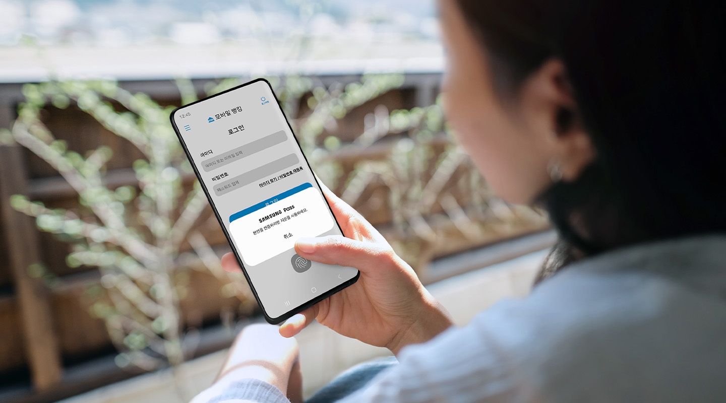 삼성 갤럭시 사용자가 은행 앱에 로그인하기 위해 Samsung Pass 팝업 메시지에 따라 지문을 인증하고 있습니다.