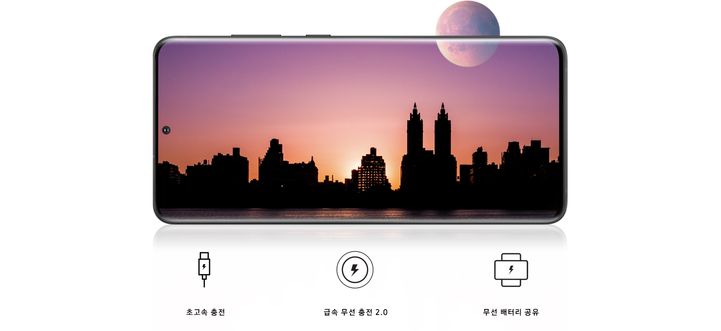 가로 모드로 된 갤럭시 S20 Ultra 5G 화면에 야간의 도시 풍경이 보입니다. 달의 절반은 화면 안쪽에, 나머지 절반은 바깥쪽에 위치해 보입니다. 급속 유선 충전을 의미하는 번개가 그려진 플러그 아이콘이 보입니다. 급속 무선 충전 2.0을 의미하는 번개가 그려진 원 모양의 아이콘이 보입니다. 무선 배터리 공유 기능을 의미하는 두 개의 휴대폰이 서로 교차되어 놓여 있는 아이콘 위에 번개가 그려진 아이콘이 보입니다.
