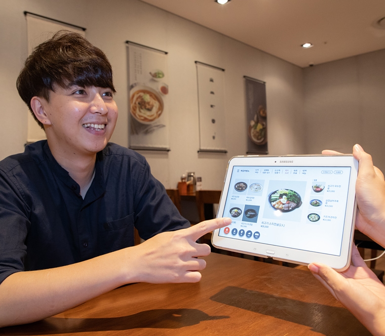 식당에서 태블릿을 통해 음식을 주문하는 고객 이미지