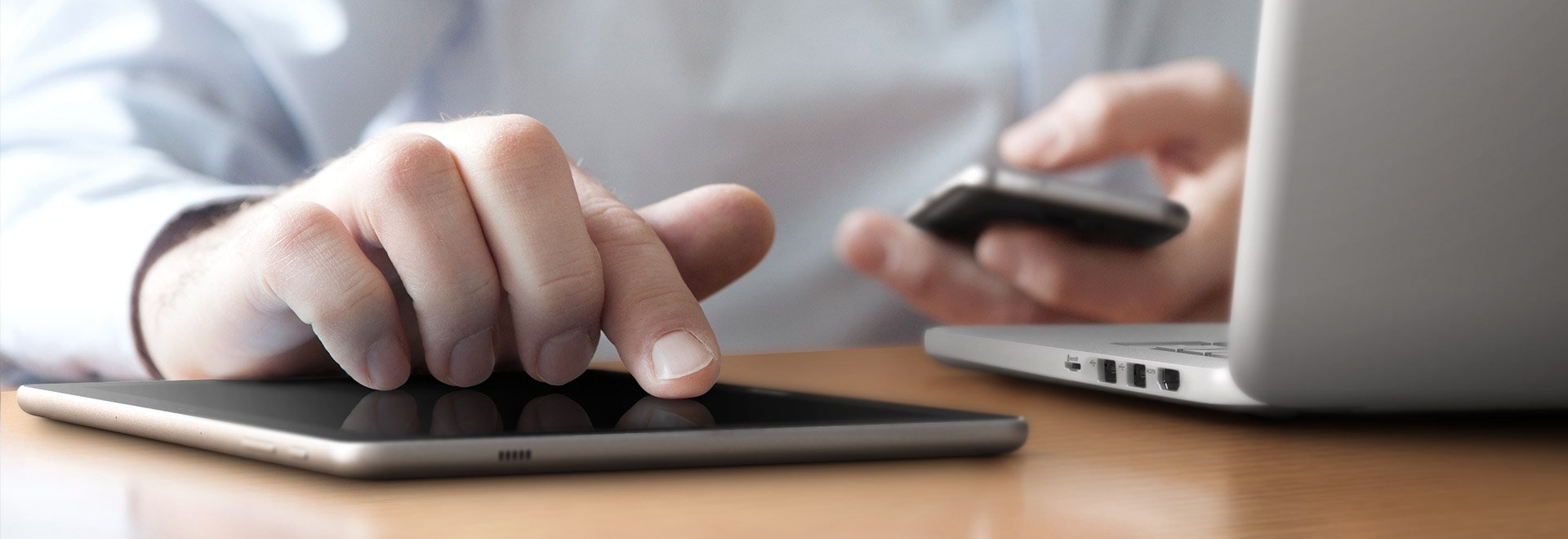 An image of a user wearing a white shirt using a smartphone and a Galaxy Book 10.6 device on a table, where a notebook is placed, with its cover open.