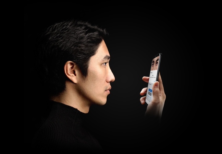 한 남성이 스마트폰의 홍채 인식을 하려고 스마트폰 화면을 응시하는 모습