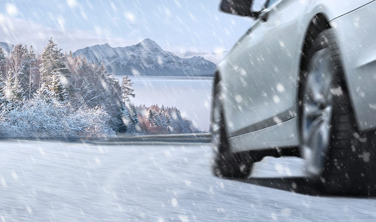 雪降る凍てつく冬の日に道路を走る車のイメージ。