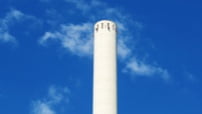 晴れ渡る空の下、工場の大きな煙突が見えます。