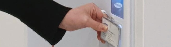 A hand is tapping the samsung donation kiosk with their employee ID to donate 1000 won