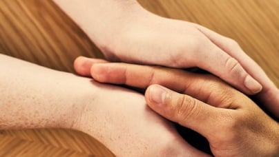 Top view of two adult hands holding a child's hand.