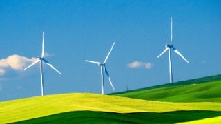 Three wind turbines seen against a blue sky.