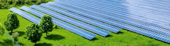 Multiple rows of solar panels seen diagonal across a green field.