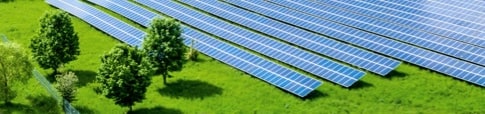 Multiple rows of solar panels seen diagonal across a green field.
